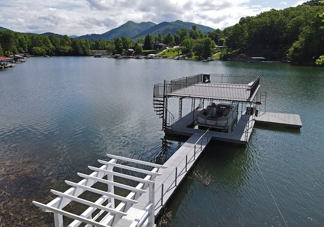 view of dock featuring a view of trees, boat lift, and a water and mountain view