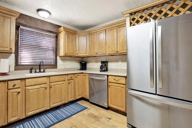 kitchen with light hardwood / wood-style floors, crown molding, stainless steel appliances, and sink