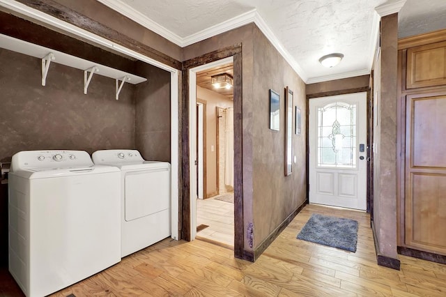 laundry area with light hardwood / wood-style floors, crown molding, and washer and dryer