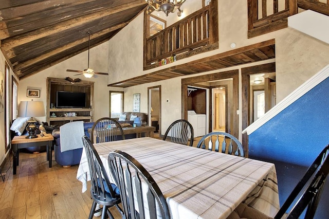 dining room with light hardwood / wood-style floors, ceiling fan with notable chandelier, and high vaulted ceiling