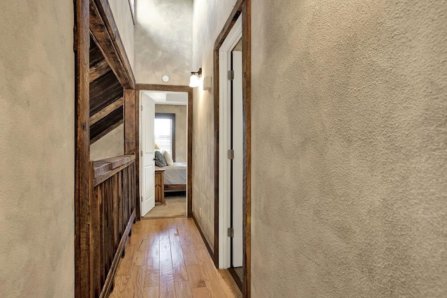 corridor with light hardwood / wood-style floors and lofted ceiling