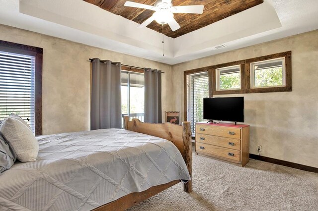 carpeted bedroom with wood ceiling, ceiling fan, and a raised ceiling