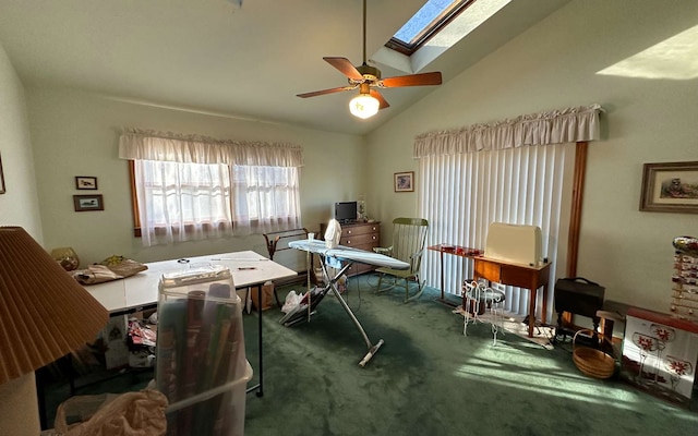 office area featuring dark colored carpet, vaulted ceiling with skylight, and ceiling fan