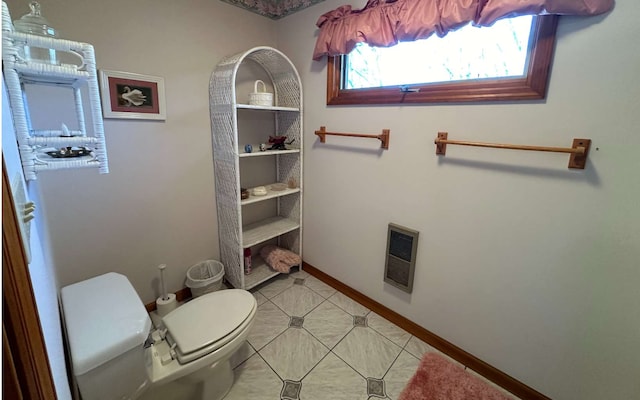 bathroom featuring heating unit, tile patterned floors, and toilet