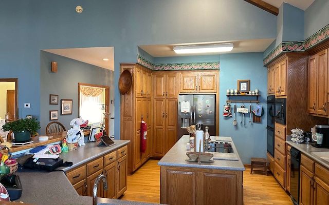 kitchen featuring high vaulted ceiling, stainless steel fridge with ice dispenser, a center island with sink, light wood-type flooring, and oven