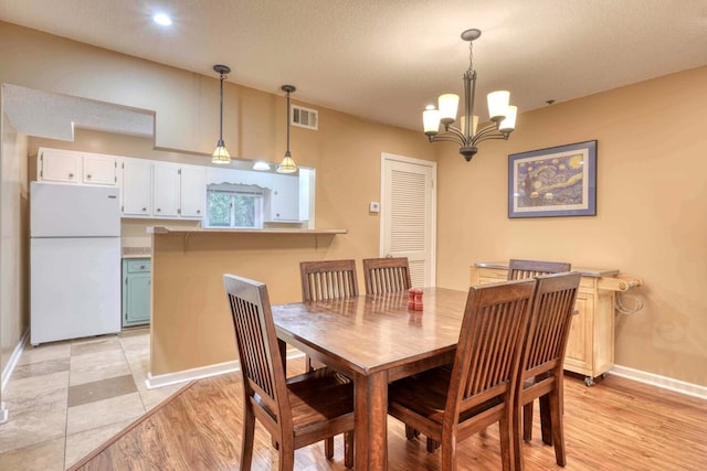 dining room featuring a textured ceiling, a chandelier, and light hardwood / wood-style flooring