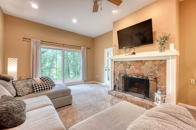 carpeted living room featuring ceiling fan, a stone fireplace, and a textured ceiling