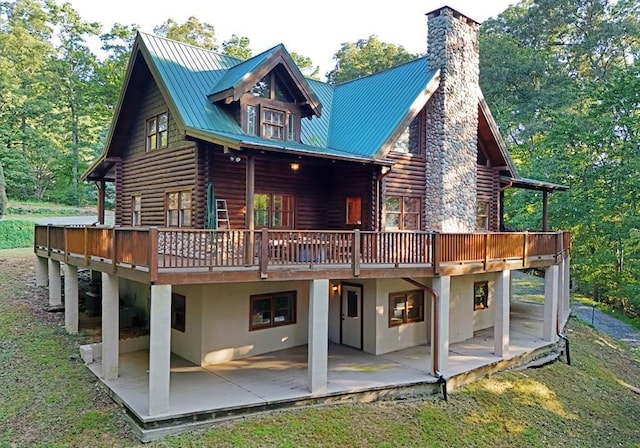 back of house featuring metal roof, log exterior, a patio area, and a wooden deck