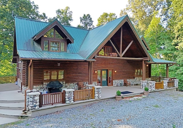 view of front facade featuring metal roof, stone siding, and log siding