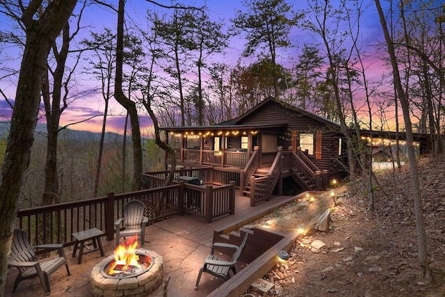 back house at dusk featuring a fire pit and a deck