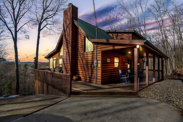 property exterior at dusk with covered porch and a deck