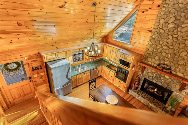 living room with wood walls, an inviting chandelier, a stone fireplace, sink, and light hardwood / wood-style flooring