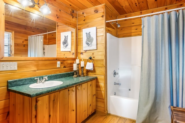 bathroom with hardwood / wood-style floors, vanity, wood walls, shower / bath combo with shower curtain, and wood ceiling