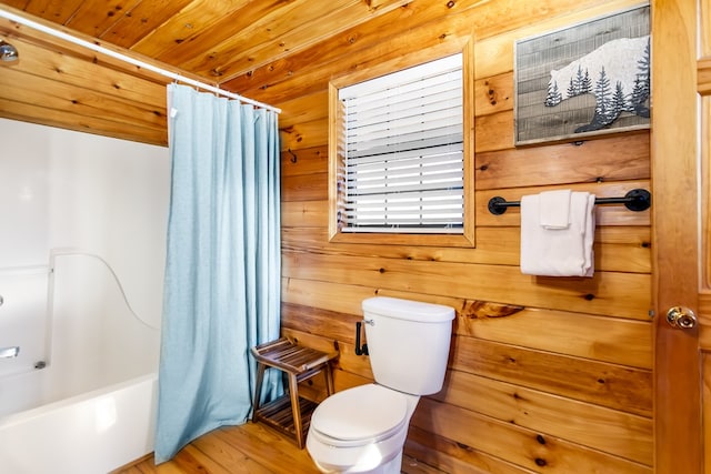 bathroom with hardwood / wood-style floors, toilet, wooden walls, shower / tub combo with curtain, and wood ceiling