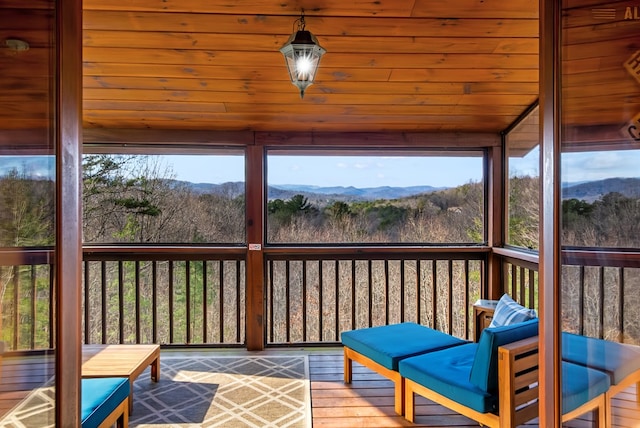 sunroom / solarium with a healthy amount of sunlight, a mountain view, and wood ceiling