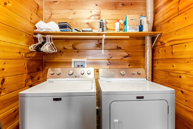 clothes washing area featuring washing machine and dryer and wood walls