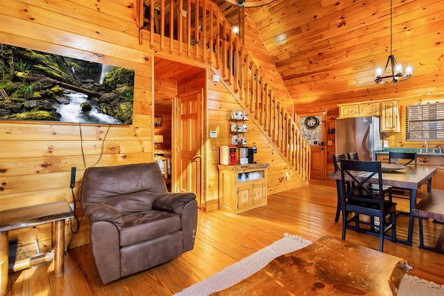 living room with light wood-type flooring, sink, an inviting chandelier, wooden ceiling, and wood walls