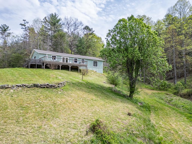 exterior space with a forest view, a wooden deck, and a front yard