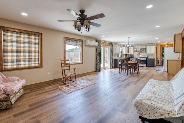 living room with recessed lighting, light wood-style flooring, ceiling fan with notable chandelier, and a wall mounted AC