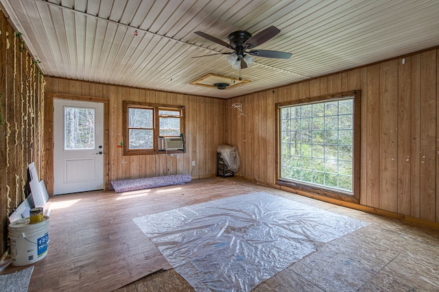 interior space featuring baseboards, wood walls, ceiling fan, and cooling unit