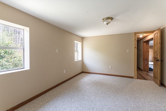 carpeted empty room with baseboards