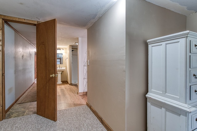 hall with baseboards and light carpet
