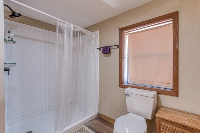 bathroom with baseboards, a shower stall, toilet, and wood finished floors
