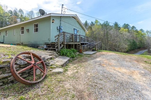 back of property featuring stairs and a deck