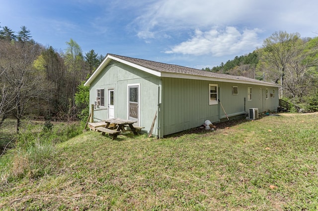 view of side of home with a lawn and cooling unit