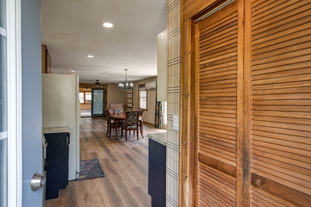 hallway featuring a notable chandelier, an AC wall unit, recessed lighting, baseboards, and wood finished floors