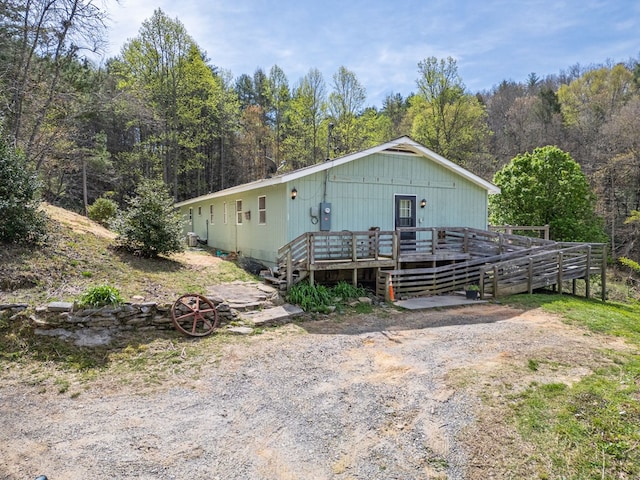 view of front of house with a view of trees and a wooden deck