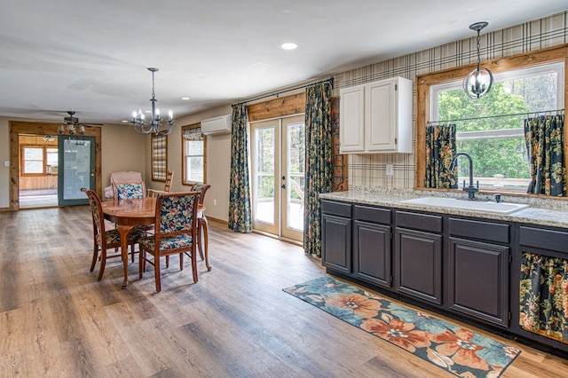 dining area with an AC wall unit, baseboards, an inviting chandelier, and french doors