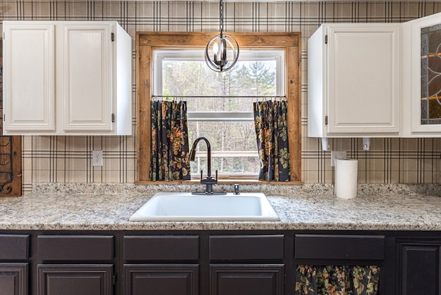 kitchen featuring a sink, glass insert cabinets, plenty of natural light, and white cabinetry