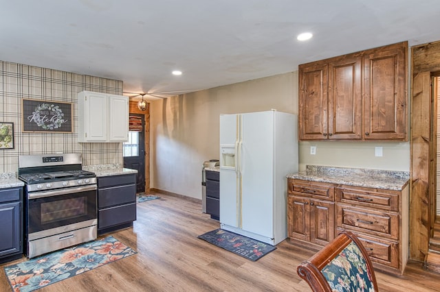 kitchen with recessed lighting, light wood-style flooring, white fridge with ice dispenser, and stainless steel gas range