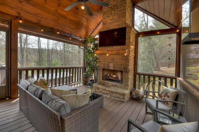 sunroom / solarium featuring an outdoor stone fireplace, ceiling fan, lofted ceiling, and wooden ceiling