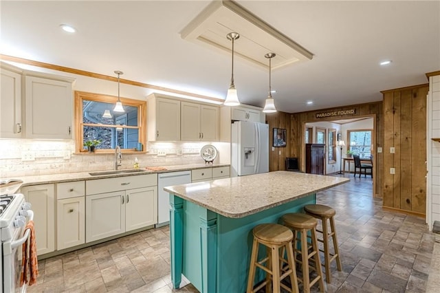 kitchen with white appliances, light stone counters, a sink, and a center island