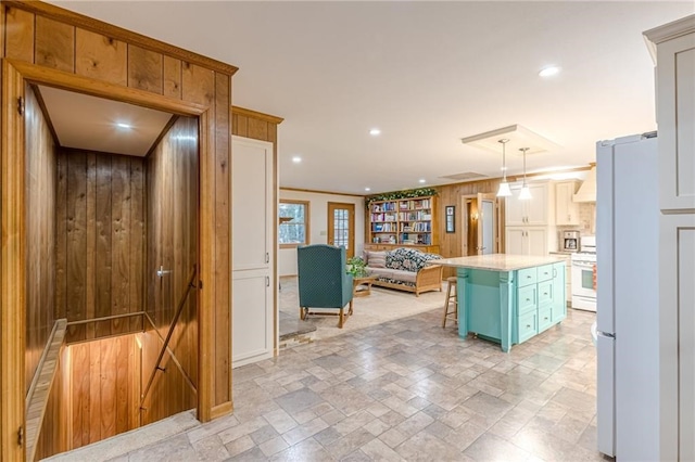 kitchen with decorative light fixtures, light countertops, a kitchen island, white appliances, and a kitchen breakfast bar