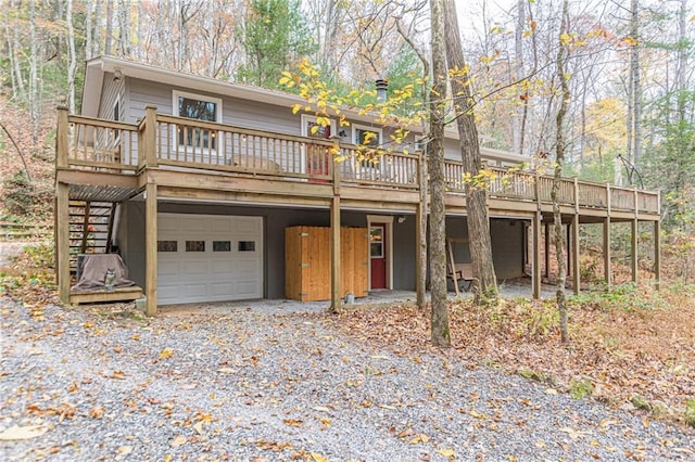 rustic home featuring gravel driveway, a deck, an attached garage, and stairs