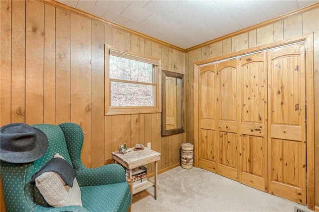 sitting room featuring crown molding, wooden walls, and carpet flooring