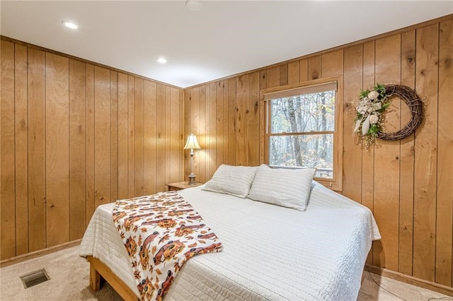 bedroom with visible vents, light carpet, and wooden walls