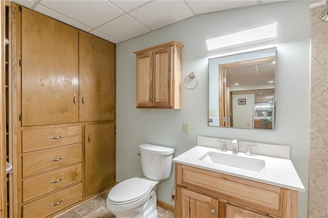 bathroom featuring toilet, a paneled ceiling, and vanity