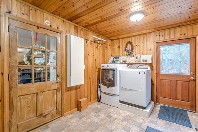 clothes washing area with laundry area, wooden walls, wood ceiling, stone finish flooring, and washer and dryer