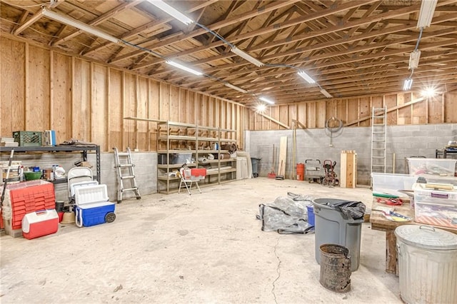 misc room with a garage and unfinished concrete flooring