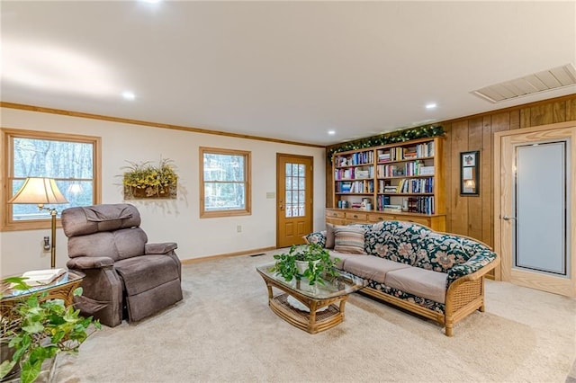 living area featuring plenty of natural light, carpet, visible vents, and crown molding