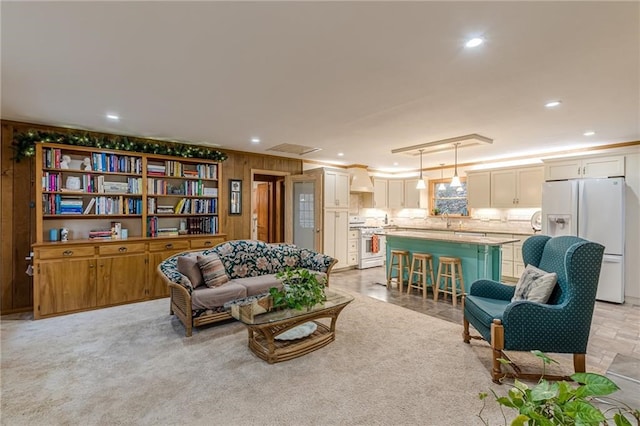 sitting room featuring ornamental molding, recessed lighting, light carpet, and wood walls