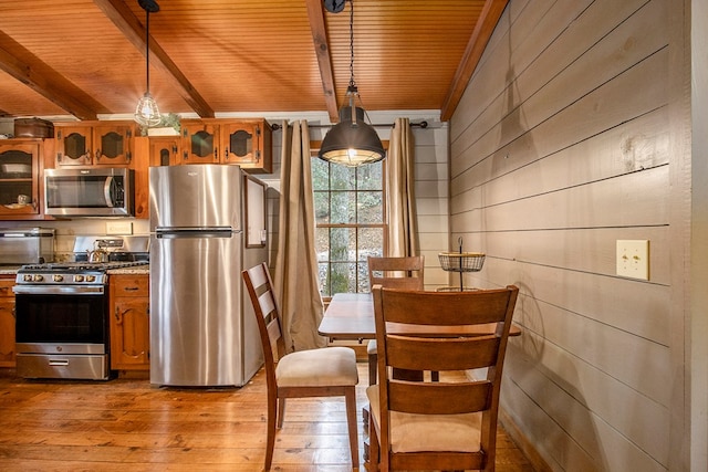 kitchen featuring wooden ceiling, hanging light fixtures, wooden walls, appliances with stainless steel finishes, and light hardwood / wood-style floors