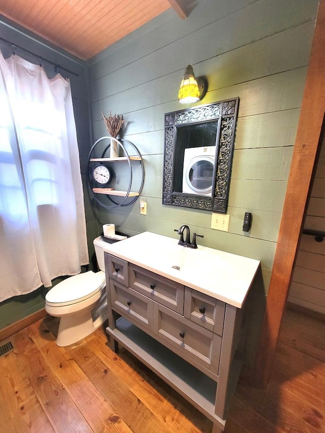 bathroom featuring wood ceiling, vanity, hardwood / wood-style floors, toilet, and washer / dryer