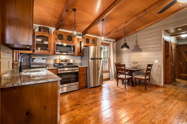 kitchen featuring sink, stainless steel appliances, lofted ceiling with beams, pendant lighting, and light wood-type flooring