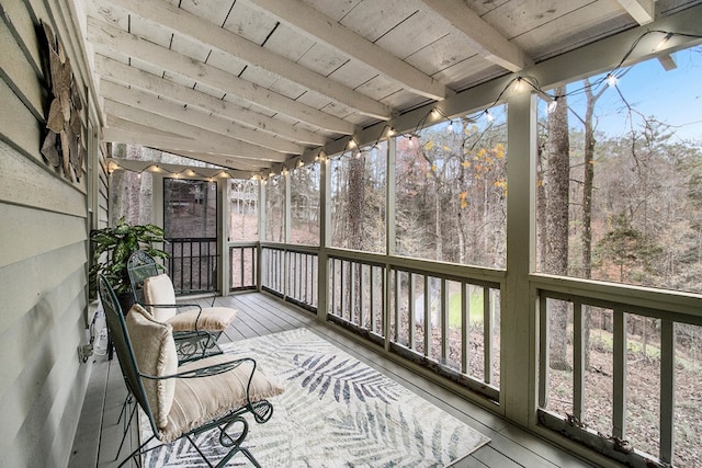 unfurnished sunroom with beam ceiling, a wealth of natural light, and wood ceiling