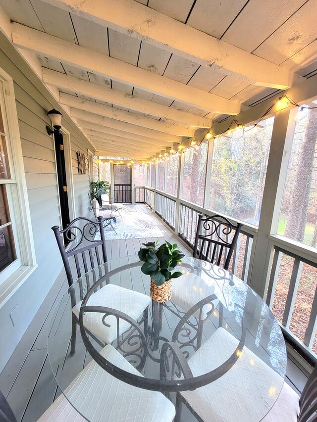 exterior space with lofted ceiling with beams, wooden ceiling, and a healthy amount of sunlight